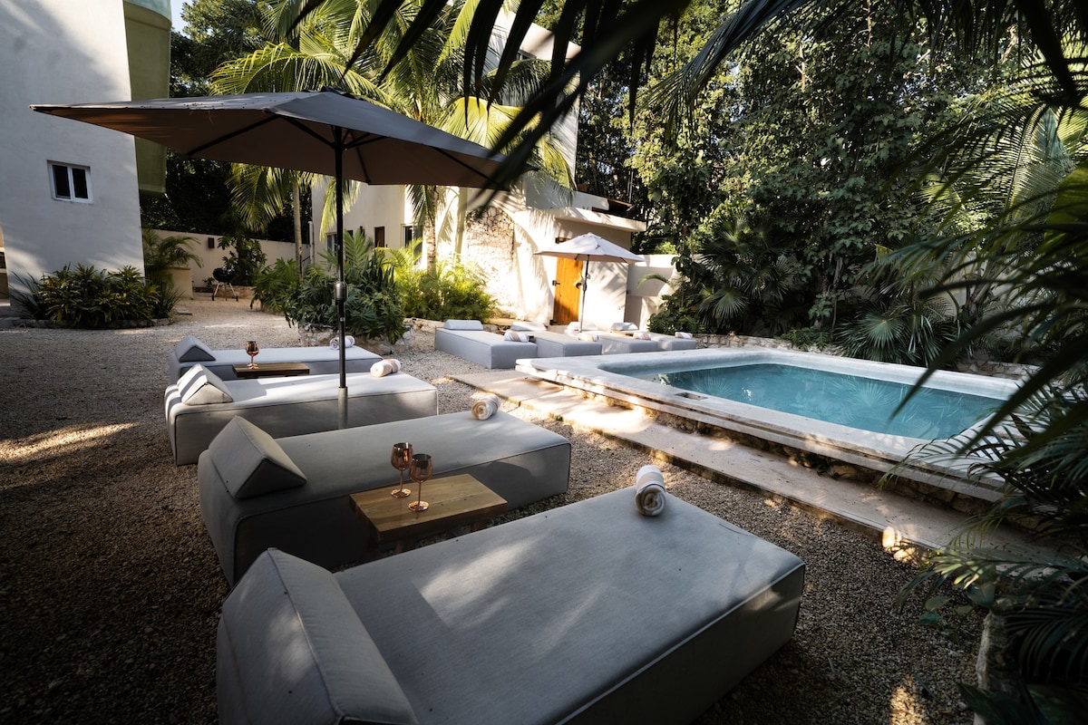 Pool and lounge area surrounded by greenery